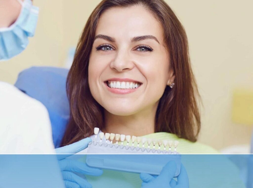 Dentist showing dental veneers colour samples to a woman showing teeth while smiling